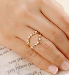 a woman's hand wearing a gold ring with leaves on the middle and sides