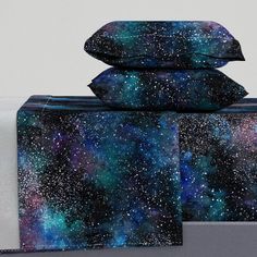 three pillows stacked on top of each other in front of a space themed pillow case