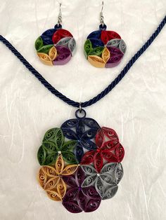 a necklace and earring set made out of colorful paper quillings on a blue cord