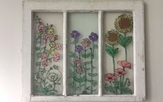 an old window with flowers painted on the glass and some white paint is hanging on the wall