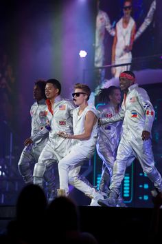 a group of men on stage with one man in the middle wearing white and red