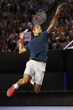 a male tennis player is jumping in the air with his racquet raised up