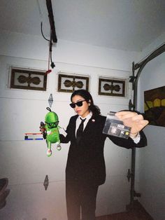 a woman in a suit and sunglasses holding a toy