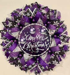 a purple and white christmas wreath with merry lettering on the front, surrounded by snowflakes