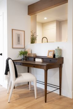 a white chair sitting next to a desk with a mirror on it's wall