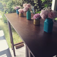 several vases filled with flowers sitting on top of a wooden table