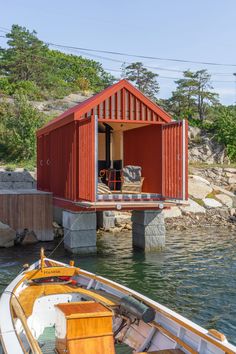 a small red house sitting on top of a body of water next to a boat