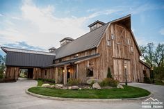 a large wooden barn sitting on top of a lush green field