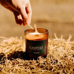 someone is lighting a candle with a match in it on the ground surrounded by straw