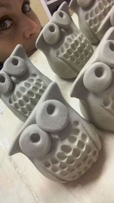 a close up of a person looking at some clay owls on a table with their eyes closed