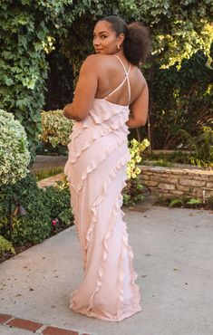 a woman in a pink dress is standing outside