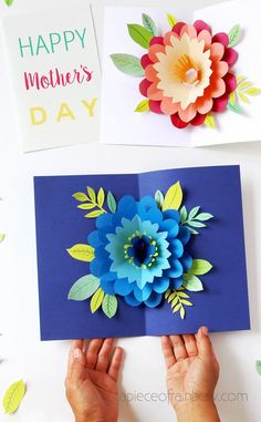 two hands holding up a card with flowers on it and the words happy mother's day