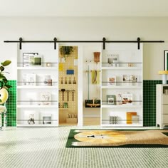 a living room with green and white walls, flooring and shelves filled with items