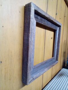 a wooden frame hanging on the side of a yellow wall next to a striped cushion