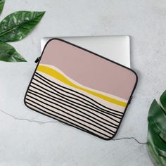 a laptop case sitting on top of a table next to a green leafy plant