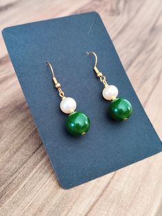 A lovely pair of minimalist dangle earrings made of a natural green jade stone, a real pearl and gold stainless steel. They are a stunning piece of jewelry, that have much more to them than just shimmer and shine.  Jade stones are referred to as the stones of luck and happiness, while pearls represent wisdom, especially wisdom gained through experience, but also calmness, integrity, loyalty, purity, and serenity. For this reason, these gorgeous dangle earrings would make a perfect birthday, anni Green Stone Earrings, Emerald Green Stone, Real Pearl Earrings, Earrings Emerald, Earrings Stone, Natural Stone Earrings, Earrings Pearl, Mothers Day Presents, Real Pearls