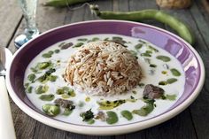 a bowl filled with rice and beans on top of a wooden table next to green peppers