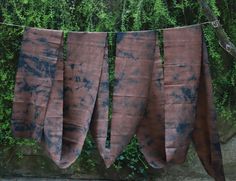 several pieces of cloth hanging on a clothes line with green bushes in the back ground