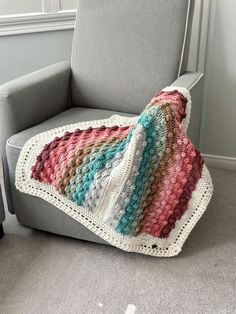 a crocheted blanket sitting on top of a gray chair