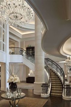 an elegant lobby with chandelier and marble staircase leading up to the second floor