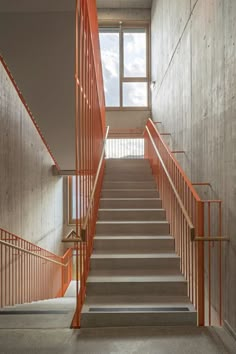 an orange staircase leading up to a window in a building with concrete walls and metal railings