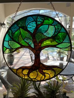 a stained glass window with a tree in the center and hanging from it's chain