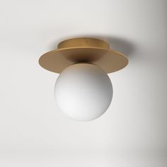 a white ball hanging from the ceiling next to a light fixture with a gold finish