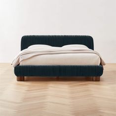 a bed sitting on top of a hard wood floor next to a white wall and wooden floors