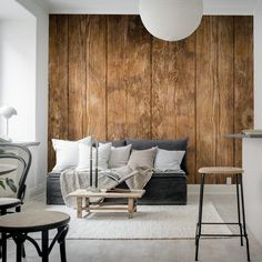 a living room with wood paneling on the wall and furniture in front of it