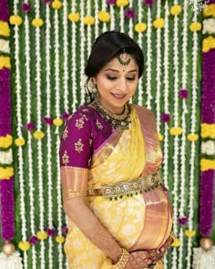 a woman in a yellow and purple sari is holding her hands on her stomach