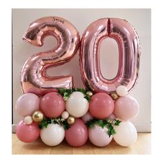 the balloon number twenty is surrounded by pink, white and gold balloons with greenery