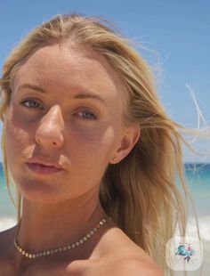 a close up of a woman on the beach with her hair blowing in the wind