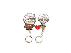 two key chains with an elderly man and woman holding a heart shaped object on them