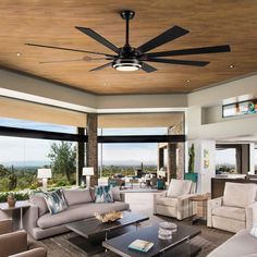 a living room filled with furniture and a ceiling fan in the middle of an open floor plan