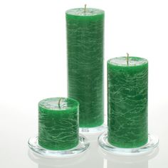 three green candles sitting next to each other on top of a glass plate with a white background