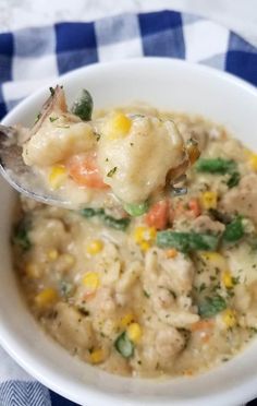 a white bowl filled with chicken and dumpling soup on top of a blue and white checkered table cloth