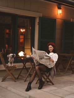 a woman sitting on a chair reading a newspaper