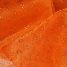 an orange sheer fabric with gold glitters on the top and bottom, as seen from above