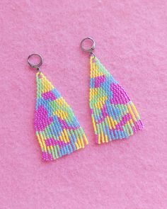 two pairs of colorful beaded earrings on pink background