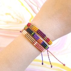 a woman's arm with three different colored beads on it and one beaded bracelet