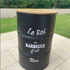 a large black barrel sitting on top of a cement floor next to a green field