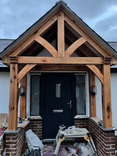 a black door sitting in the middle of a wooden frame structure next to a brick building