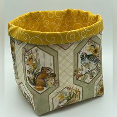 a small basket with animals and flowers on the inside, sitting on a white surface