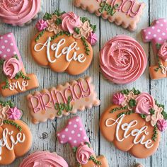 decorated cookies are arranged on a white table with pink and orange decorations, such as roses