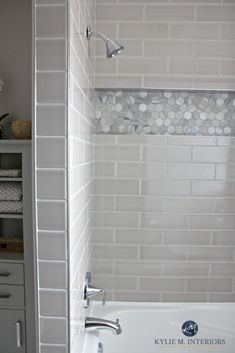 a white bath tub sitting under a window next to a shelf filled with towels and other items