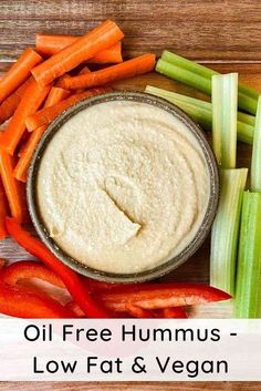 a bowl of hummus next to carrots, celery and red peppers