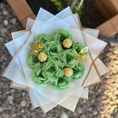 a bunch of green flowers sitting on top of a white paper plate with gold decorations