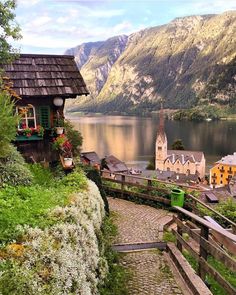 a scenic view of a small village on the edge of a lake with mountains in the background