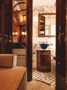 a bathroom with marble walls and flooring next to a bed in a room that has a mirror on the wall