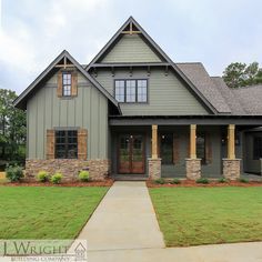 a house that is in the grass and has stone pillars on each side of it